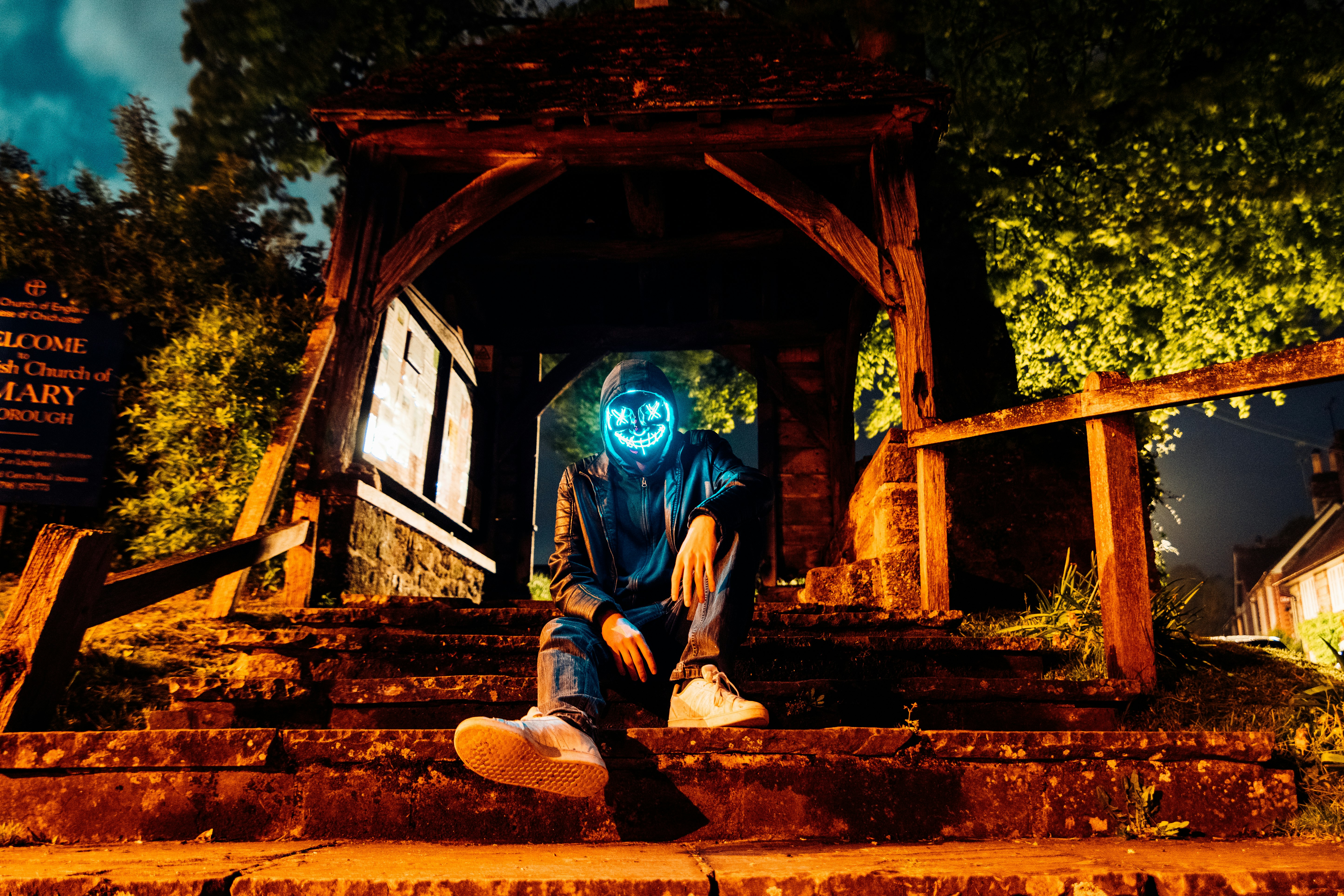 man in blue jacket and black pants sitting on brown concrete stairs